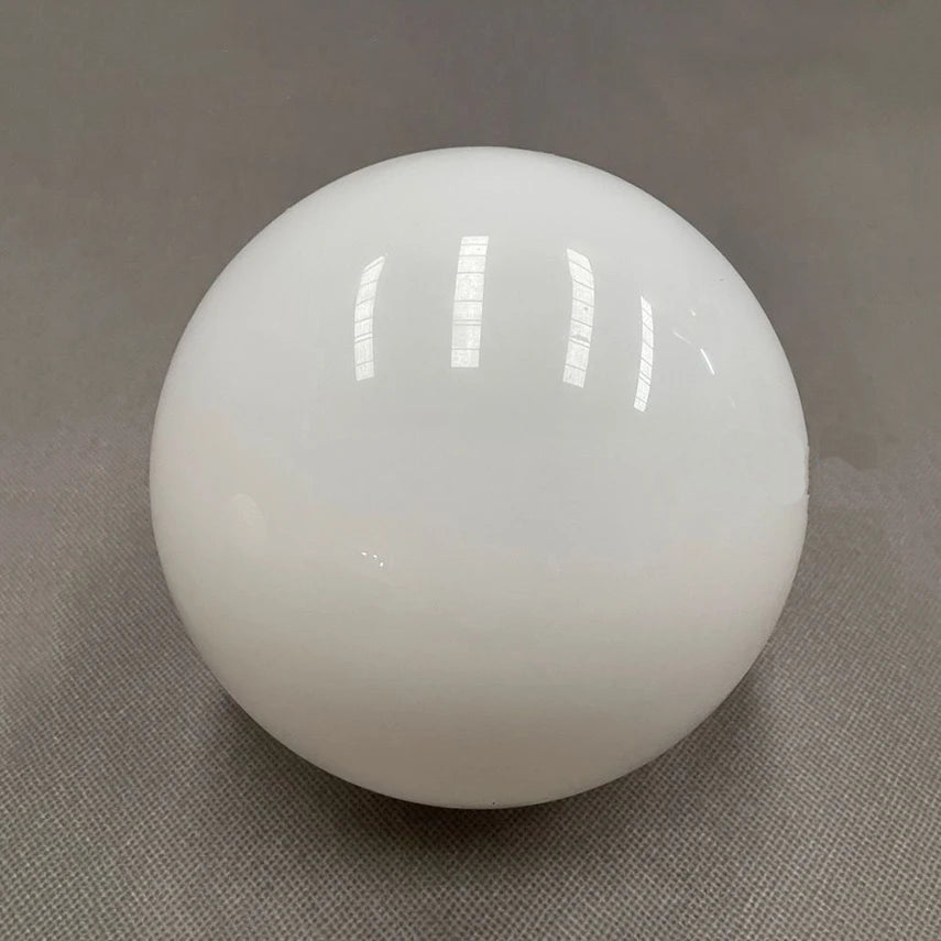 A white, opaque glass sphere with reflections of overhead lights.