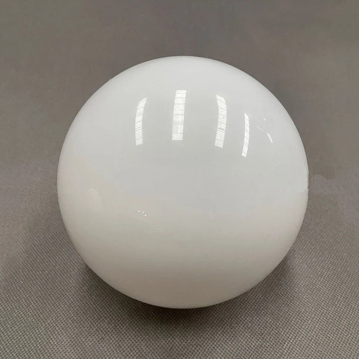 A white, opaque glass sphere with reflections of overhead lights.