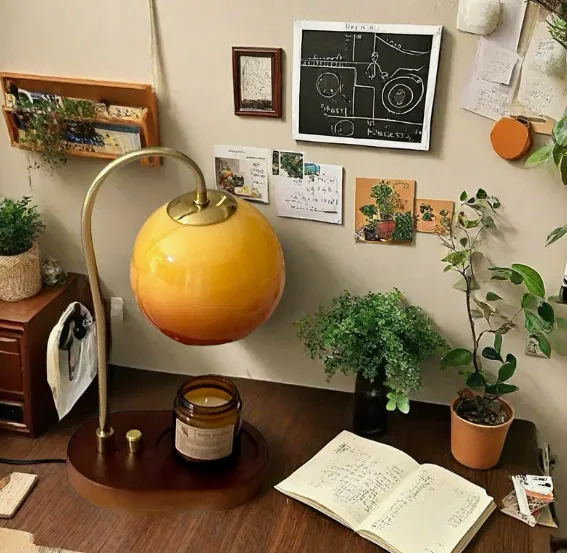 Adjustable electric candle warmer lamp with a gradient orange globe shade on a wooden base.
