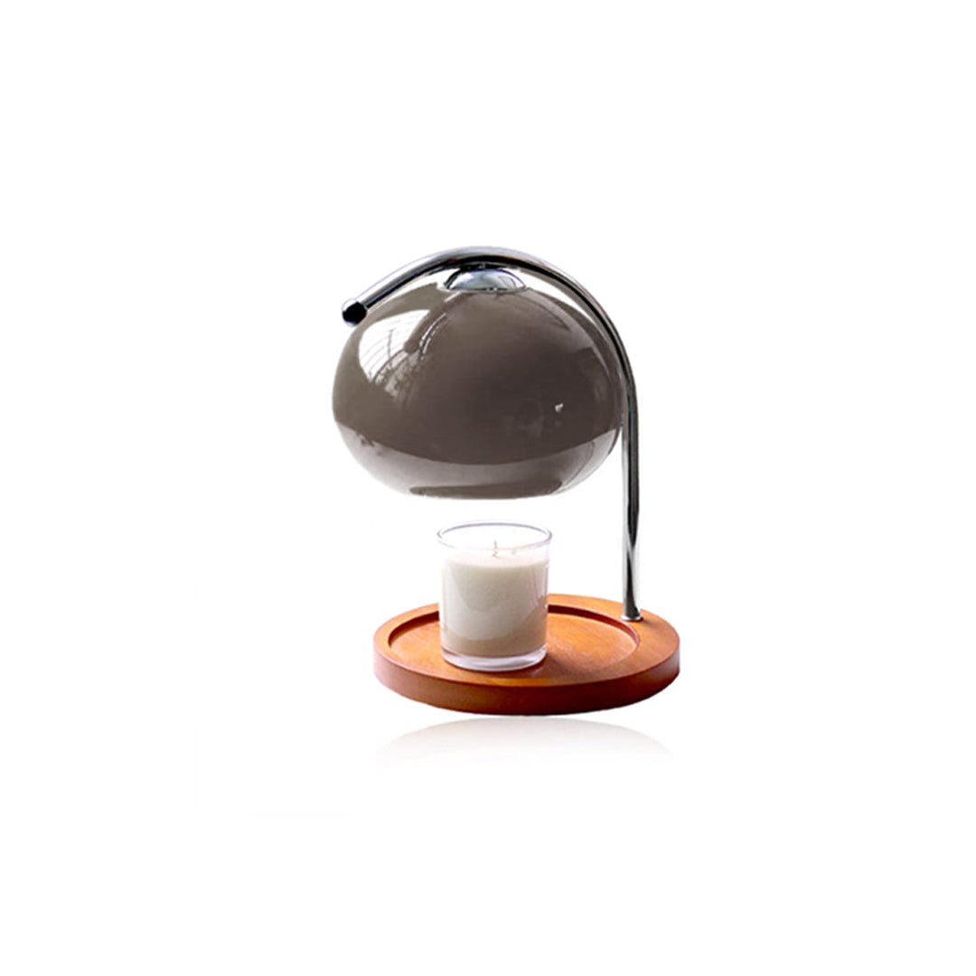 Metal and glass candle warmer lamp with a wooden base and a lit candle.