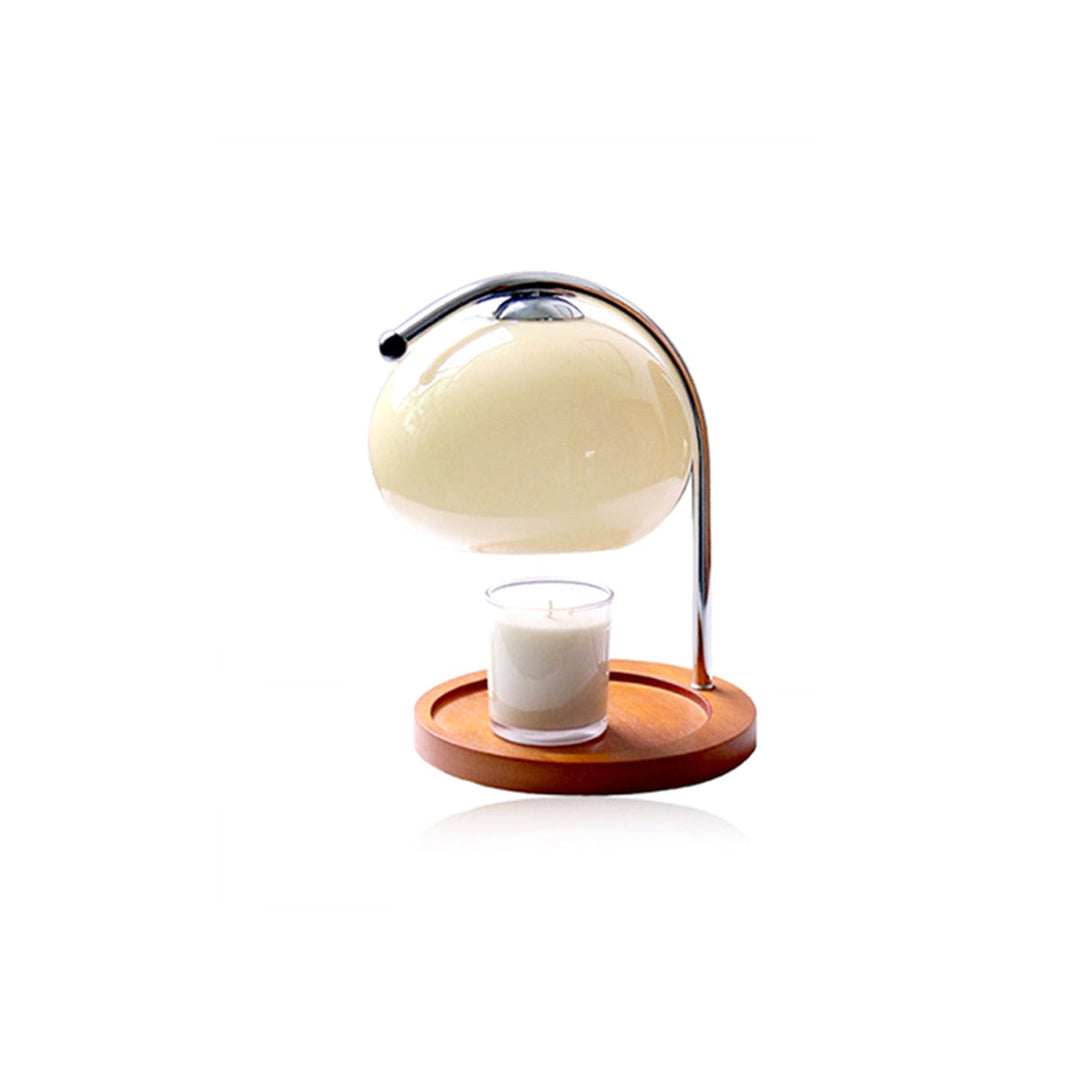 Metal and glass candle warmer lamp with a wooden base and a lit candle.