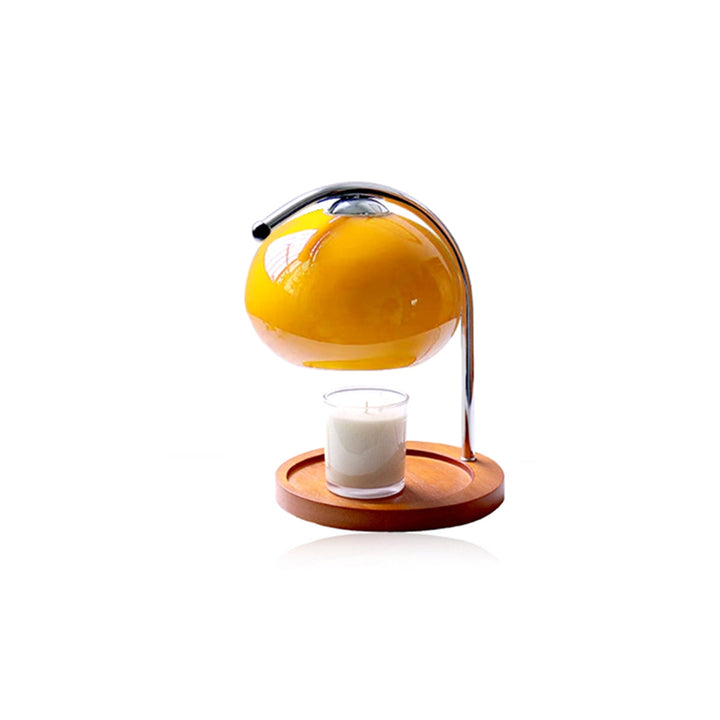Yellow glass dome candle warmer lamp with a metal arch over a wooden base and a lit candle.