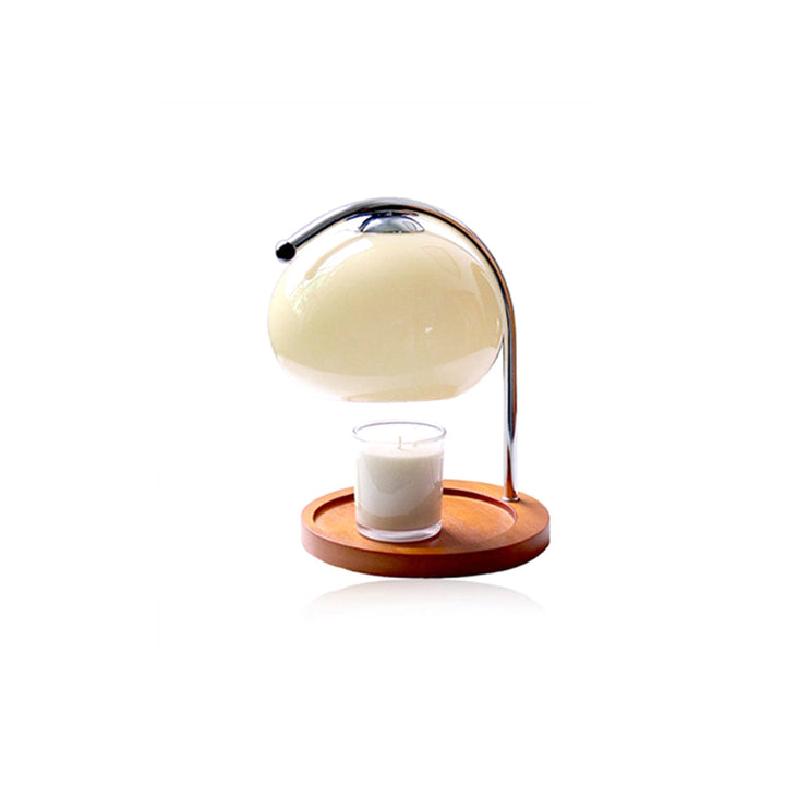 Metal and glass candle warmer lamp with a wooden base and a lit candle.