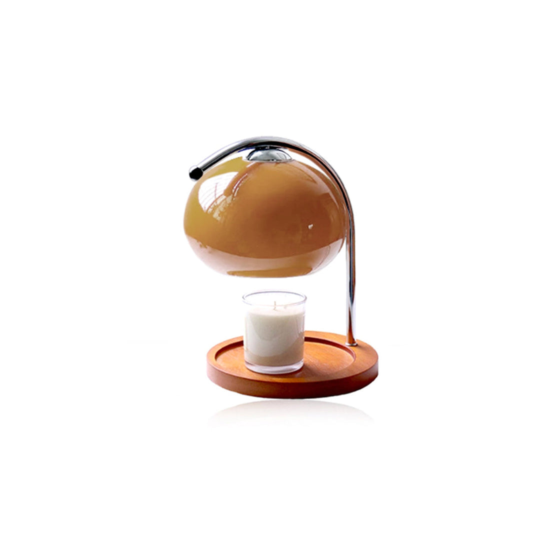 Metal and glass candle warmer lamp with a wooden base and a lit candle.
