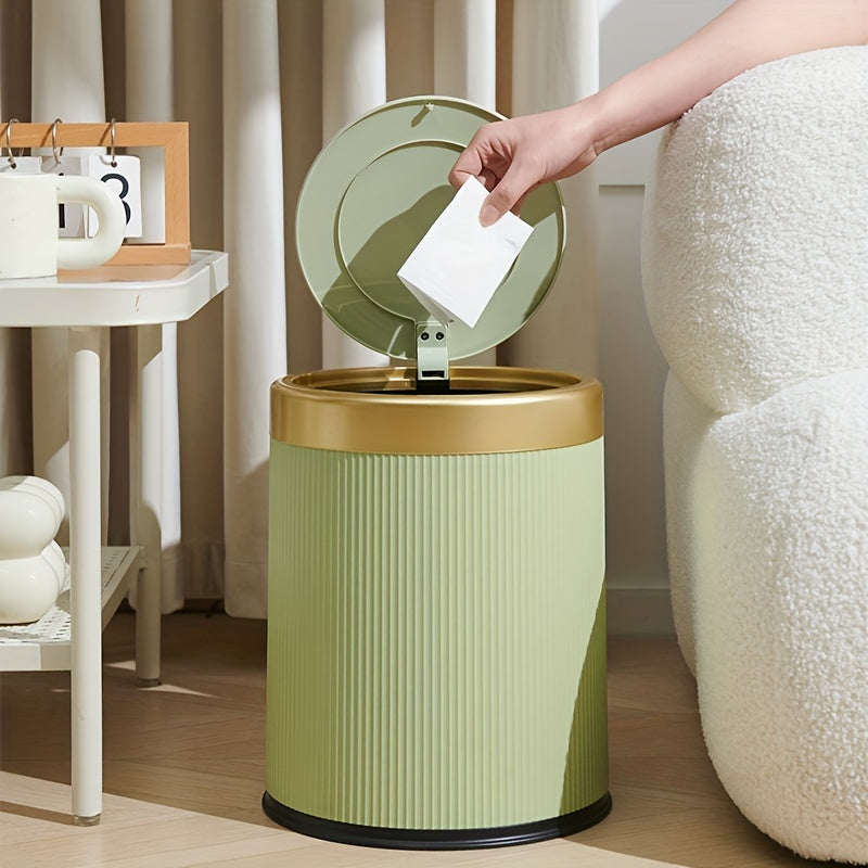 Green oval trash can with a gold rim and lid, a hand is dropping a piece of paper into it.