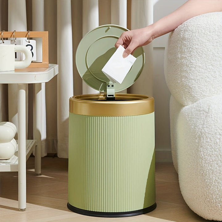 Green oval trash can with a gold rim and lid, a hand is dropping a piece of paper into it.
