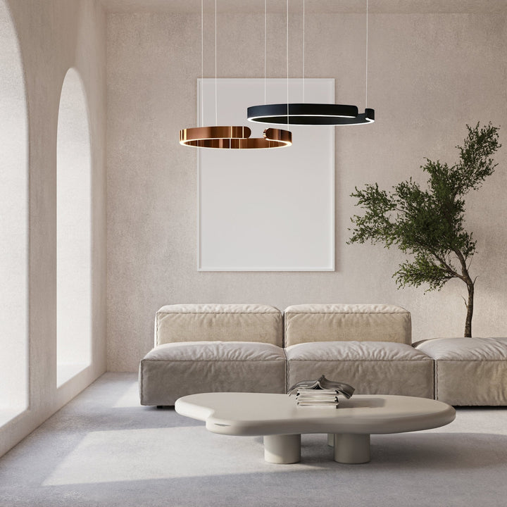 Two modern metal pendant lights, one copper and one black, hang above a sofa and coffee table.