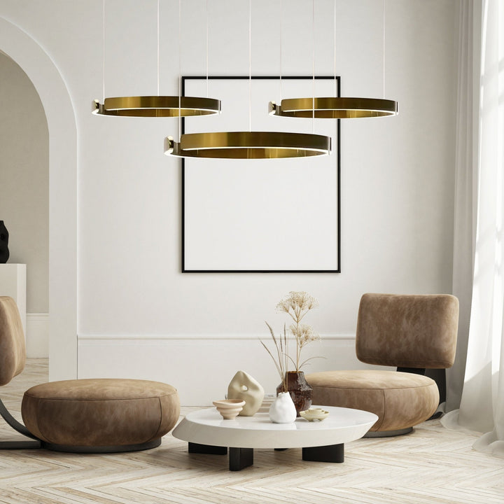 Three modern brass ring pendant lights with integrated LEDs hang above a coffee table.