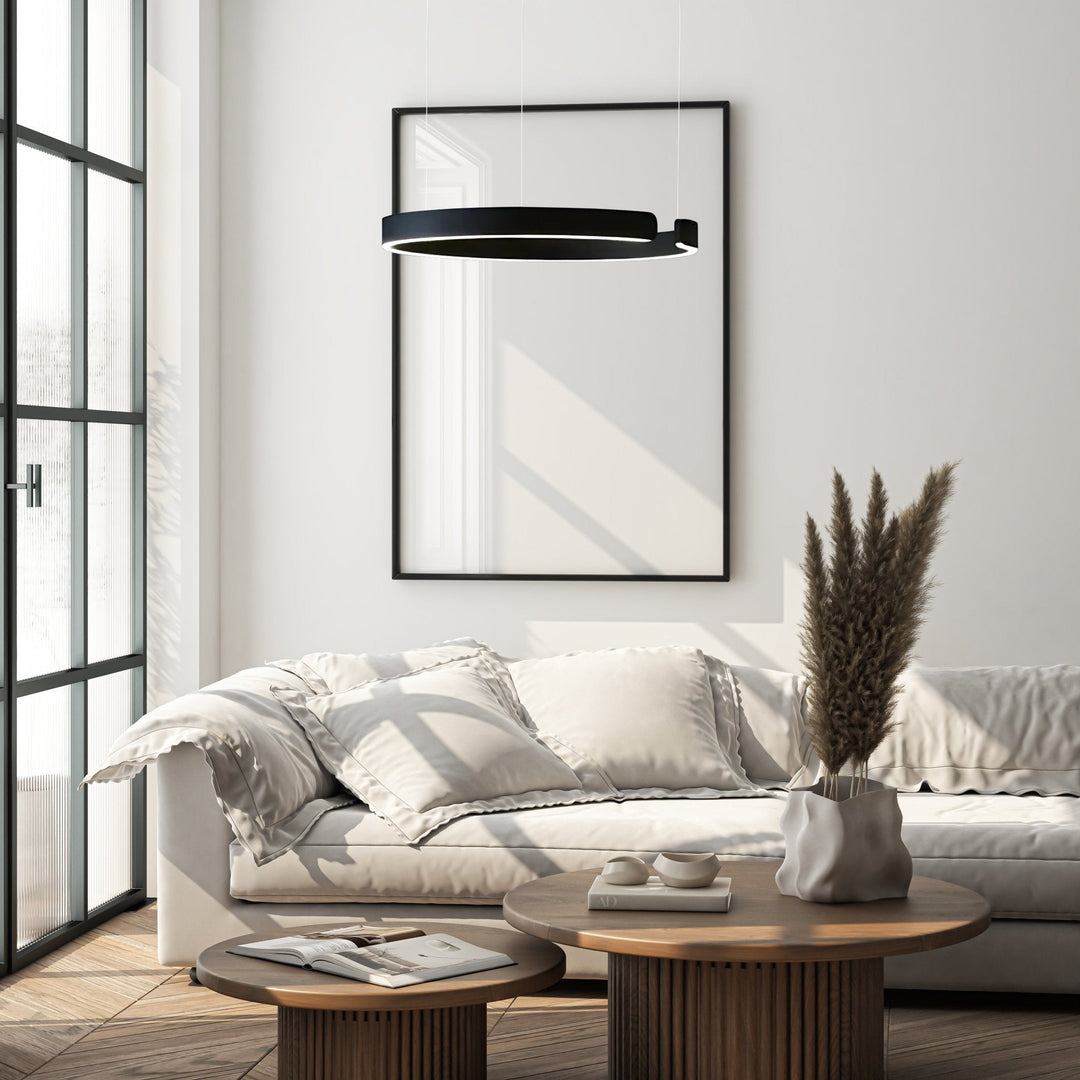 Modern black metal pendant light with integrated LED, hanging above a sofa.
