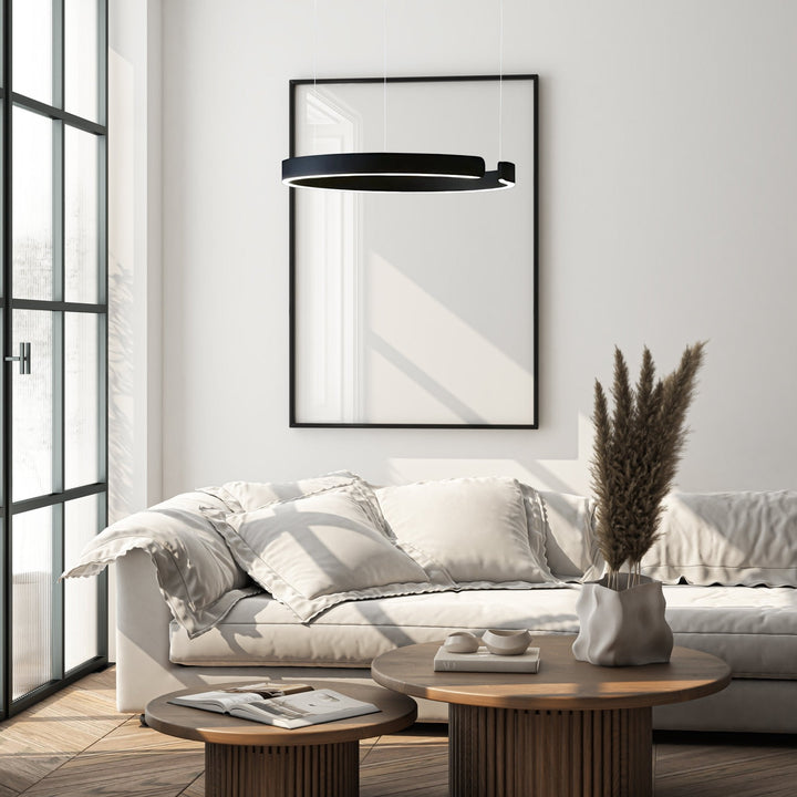 Modern black metal pendant light with integrated LED, hanging above a sofa.