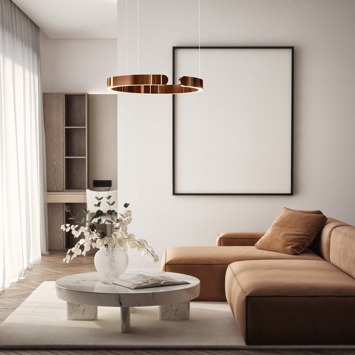 Modern metal pendant light with a copper finish hanging above a living room.