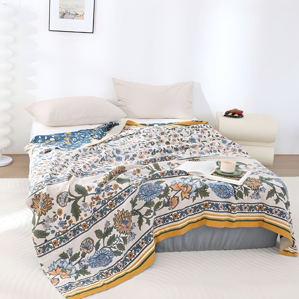 Meadow Bliss Boho Floral Blanket with a blue and white floral pattern, draped on a bed with pillows.