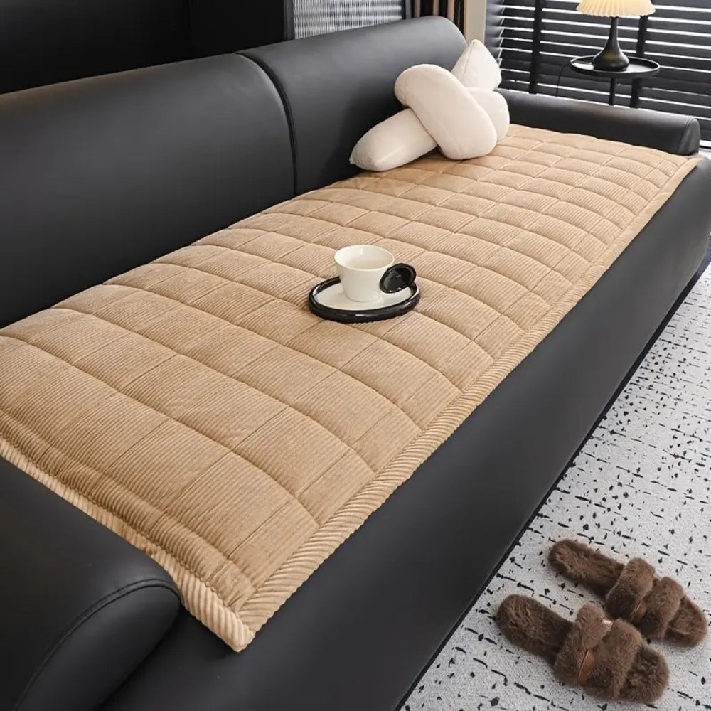 Tan quilted microfiber couch cover mat with a white cup and saucer on it.