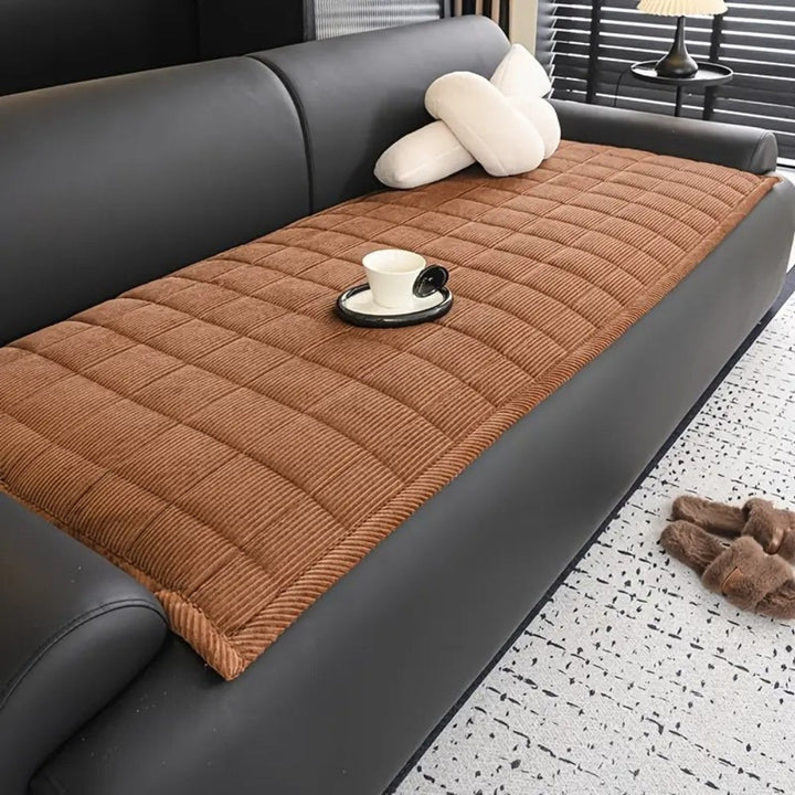Brown quilted microfiber couch cover mat with a white cup and saucer on it.