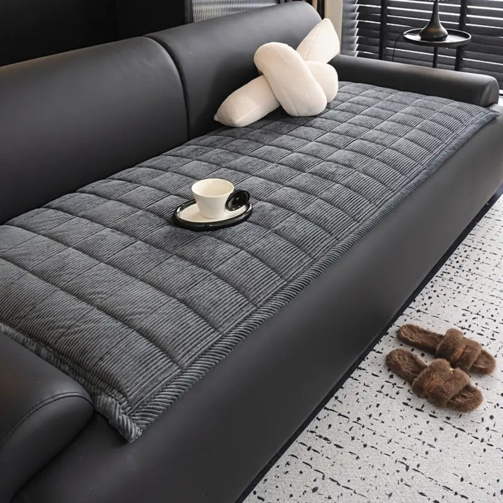 Gray quilted microfiber couch cover mat with a cup and saucer on it.