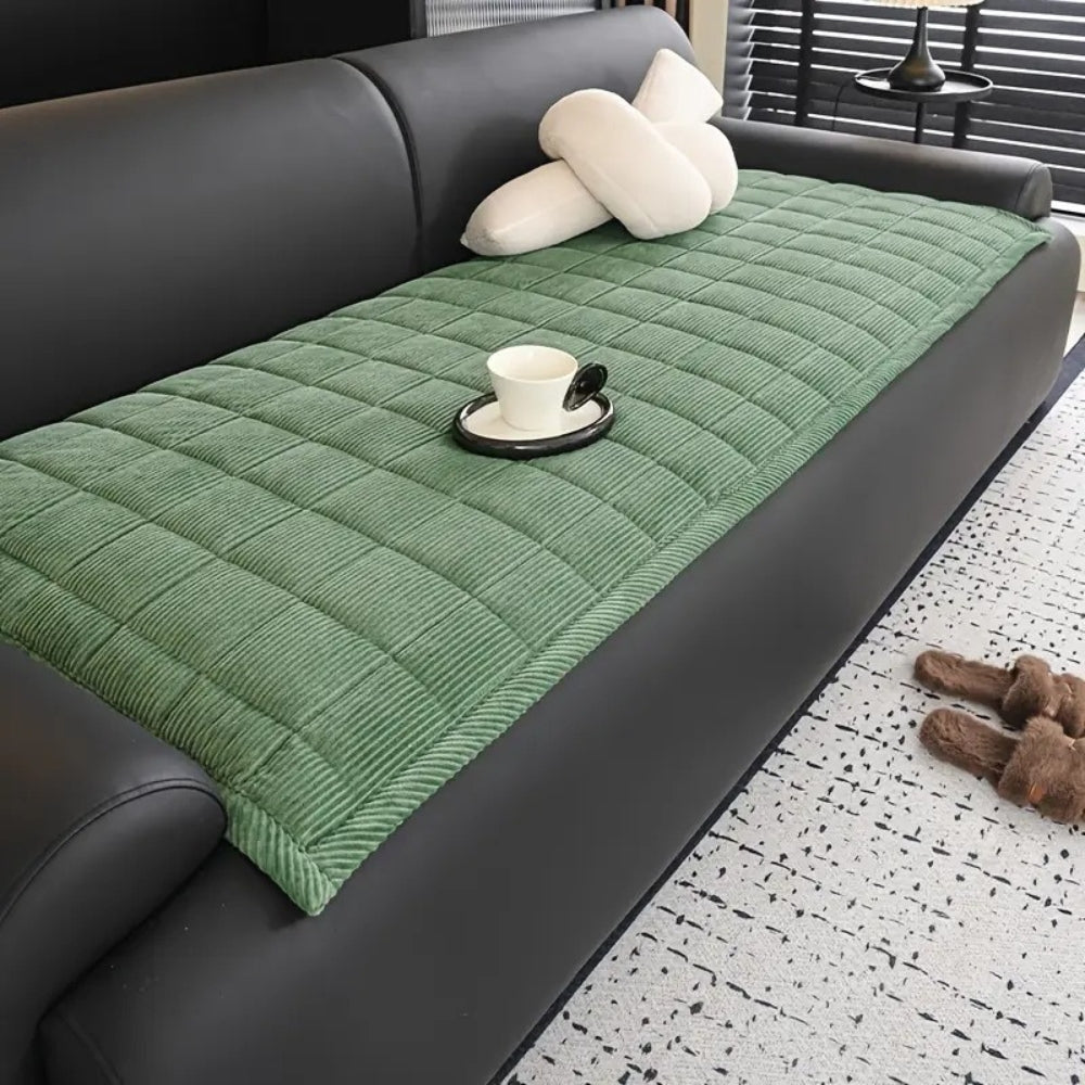 Green quilted microfiber couch cover mat with a white cup and saucer on it.