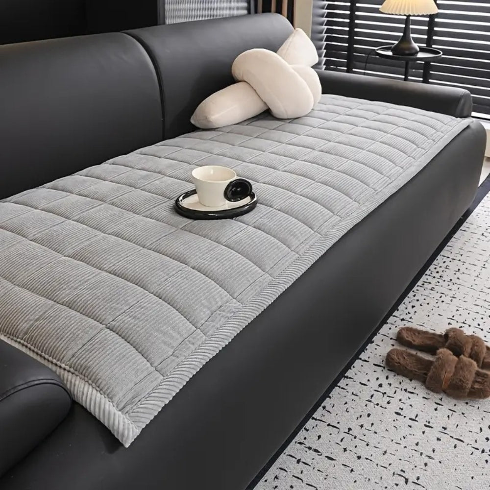 Gray quilted microfiber couch cover mat with a cup and saucer on it.