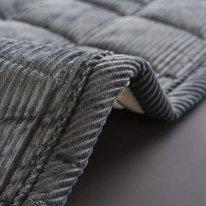 Close-up of a gray quilted couch cover mat with a soft microfiber texture.
