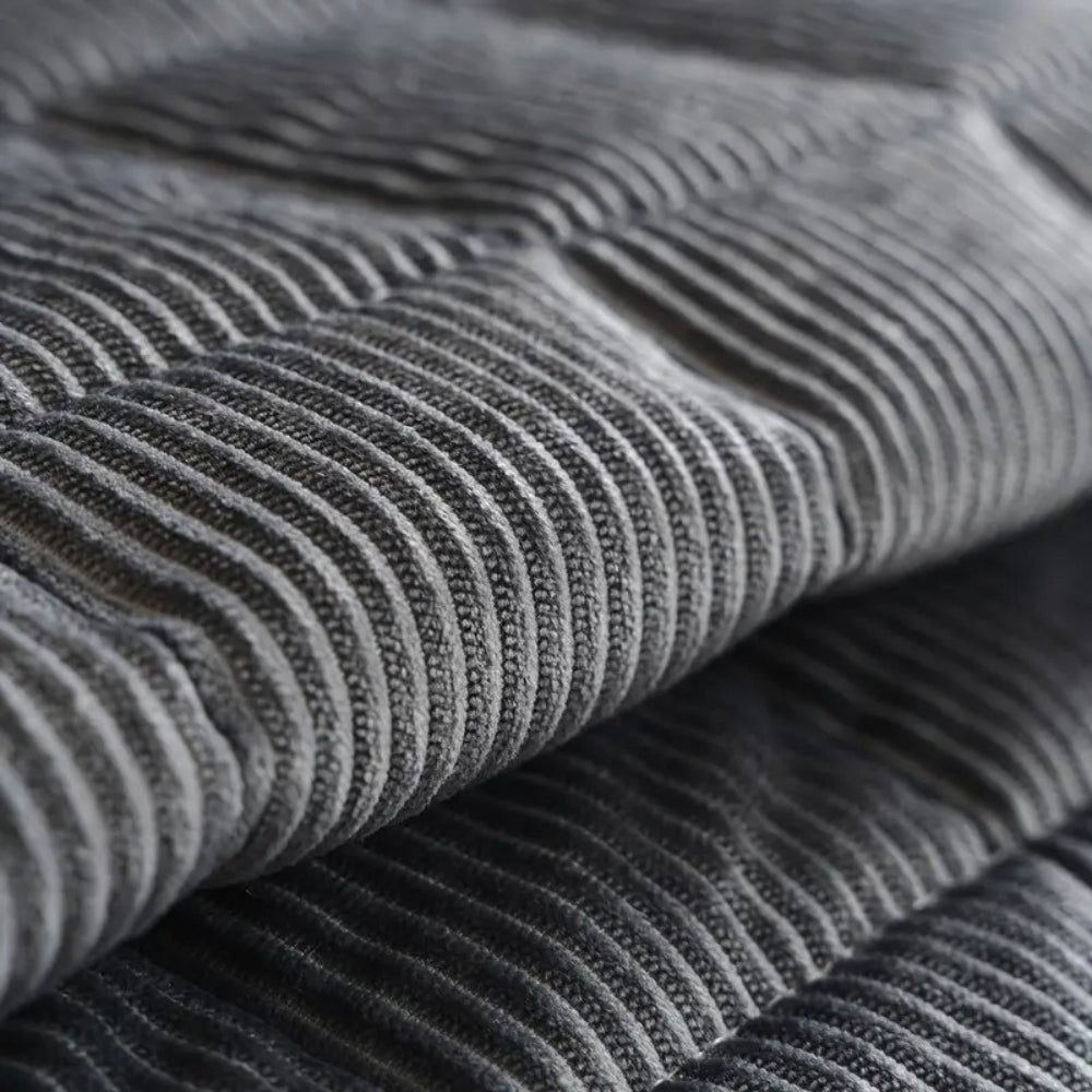 Close-up of a quilted grey microfiber couch cover mat with a ribbed texture.