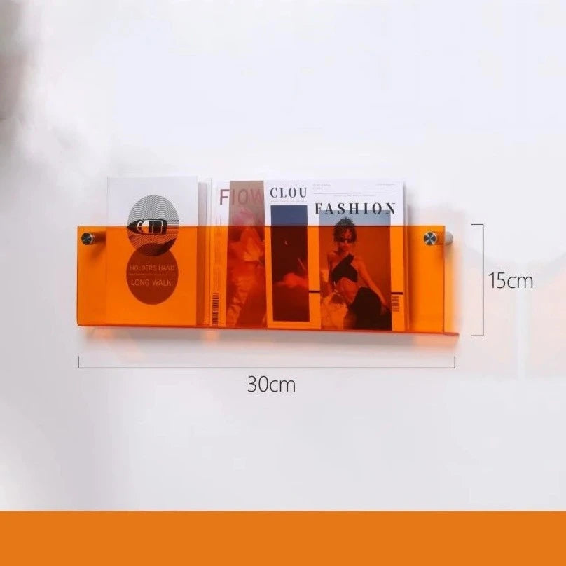 Orange acrylic floating shelf, 30cm long and 15cm high, holding magazines.