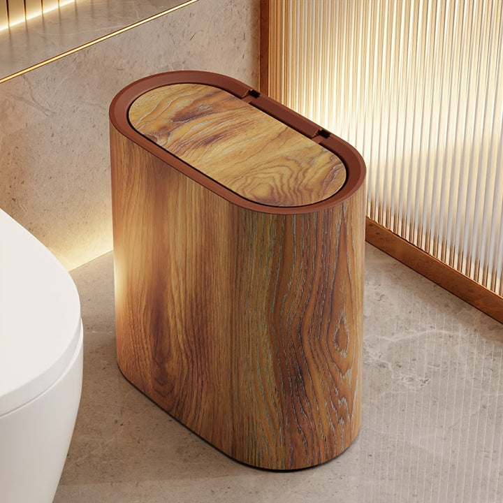 Oval trash can with a wood-grain pattern and a brown lid, placed next to a toilet.