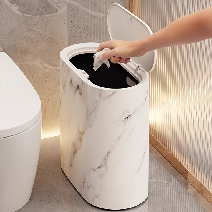 Modern marble trash can with an open lid and a hand dropping in a tissue.