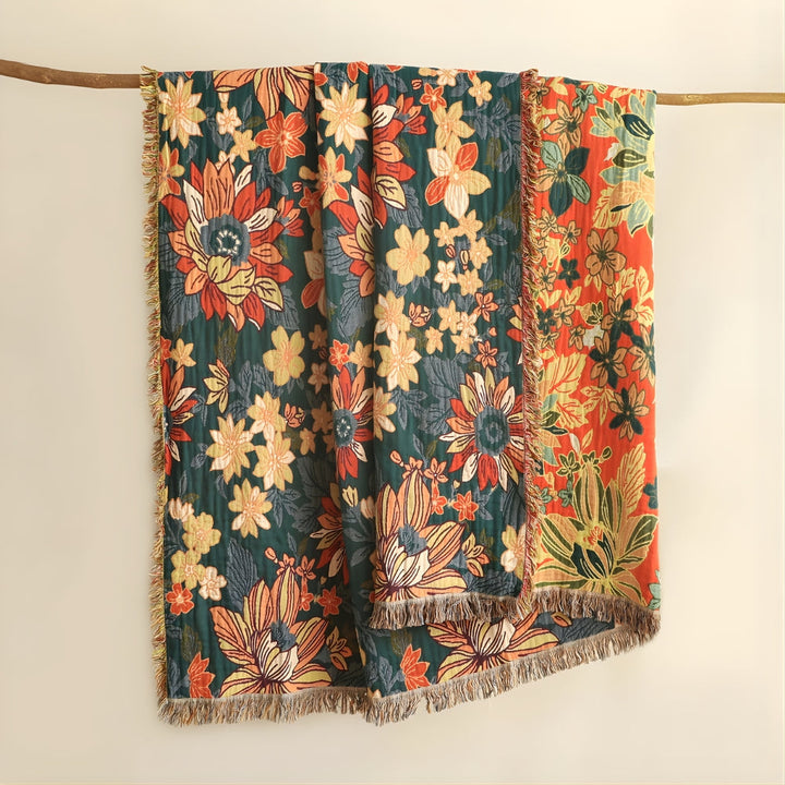 Two-sided floral cotton throw blanket with tassels, one side green, the other orange.