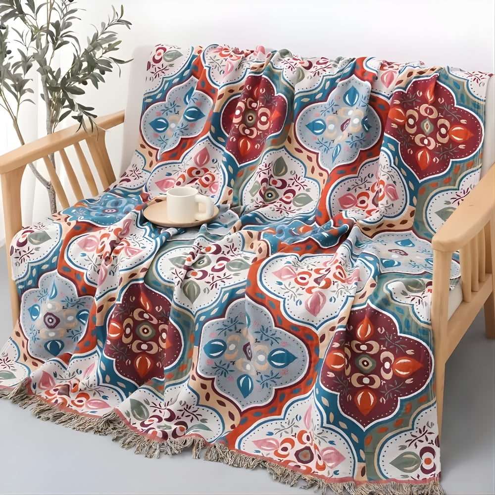 A colorful Moroccan mosaic patterned cotton blanket with tassels draped over a wooden chair.