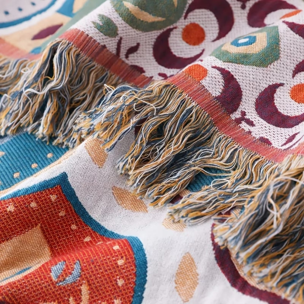Close-up of a woven cotton blanket with a Moroccan mosaic pattern and fringed edges.
