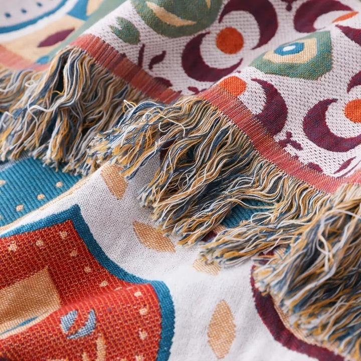 Close-up of a woven cotton blanket with a Moroccan mosaic pattern and fringed edges.