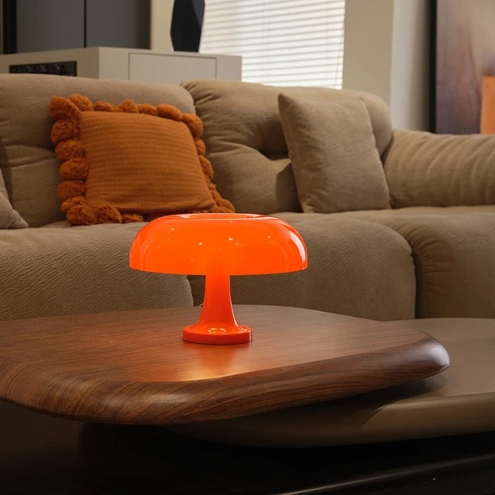 Orange mushroom-shaped LED table lamp on a wooden coffee table.