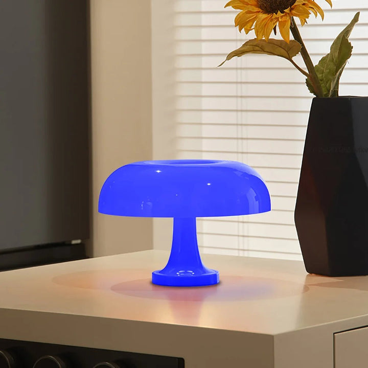 Blue mushroom-shaped LED table lamp with a soft ambient glow on a table.