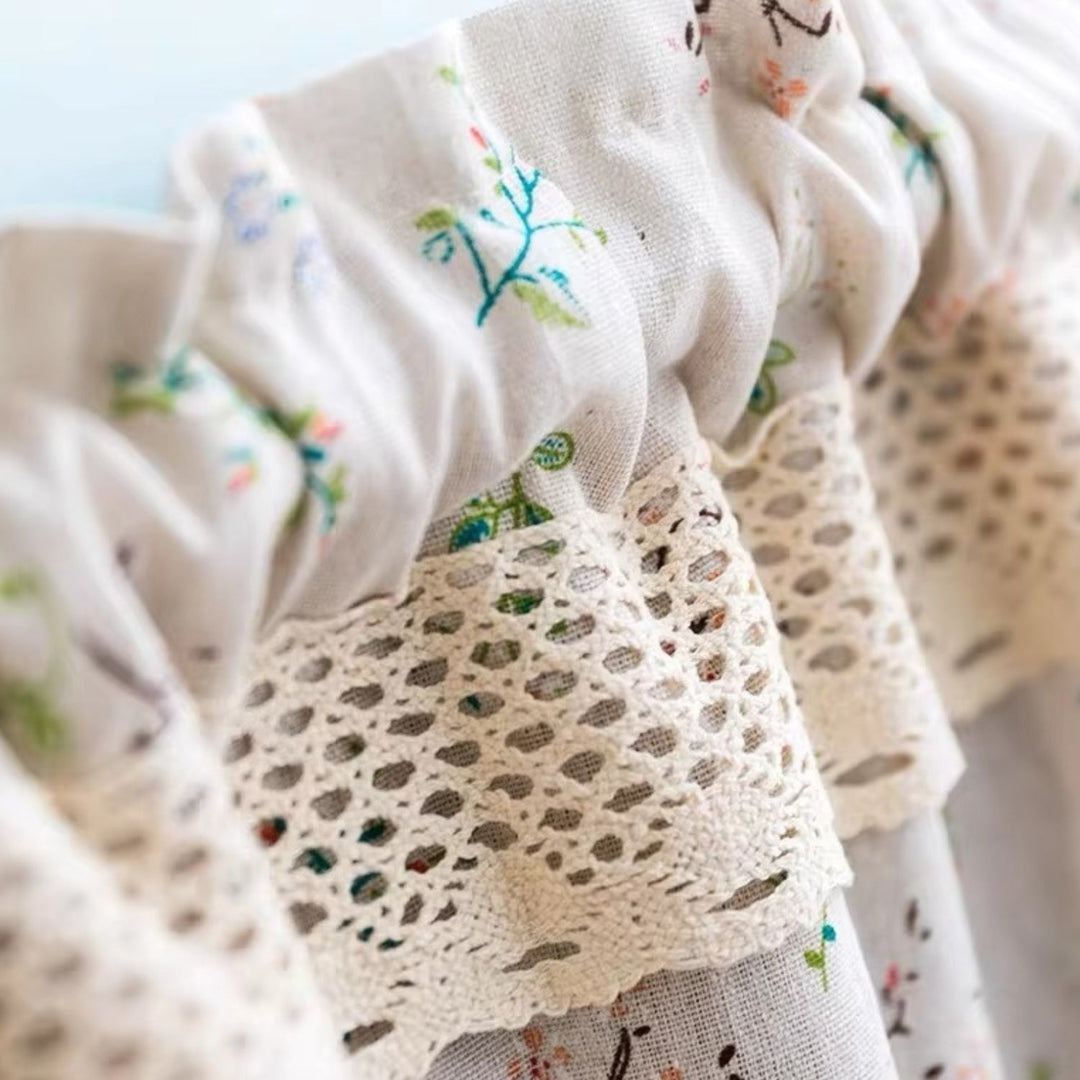 Close-up of a white kitchen curtain with a floral pattern and lace trim.