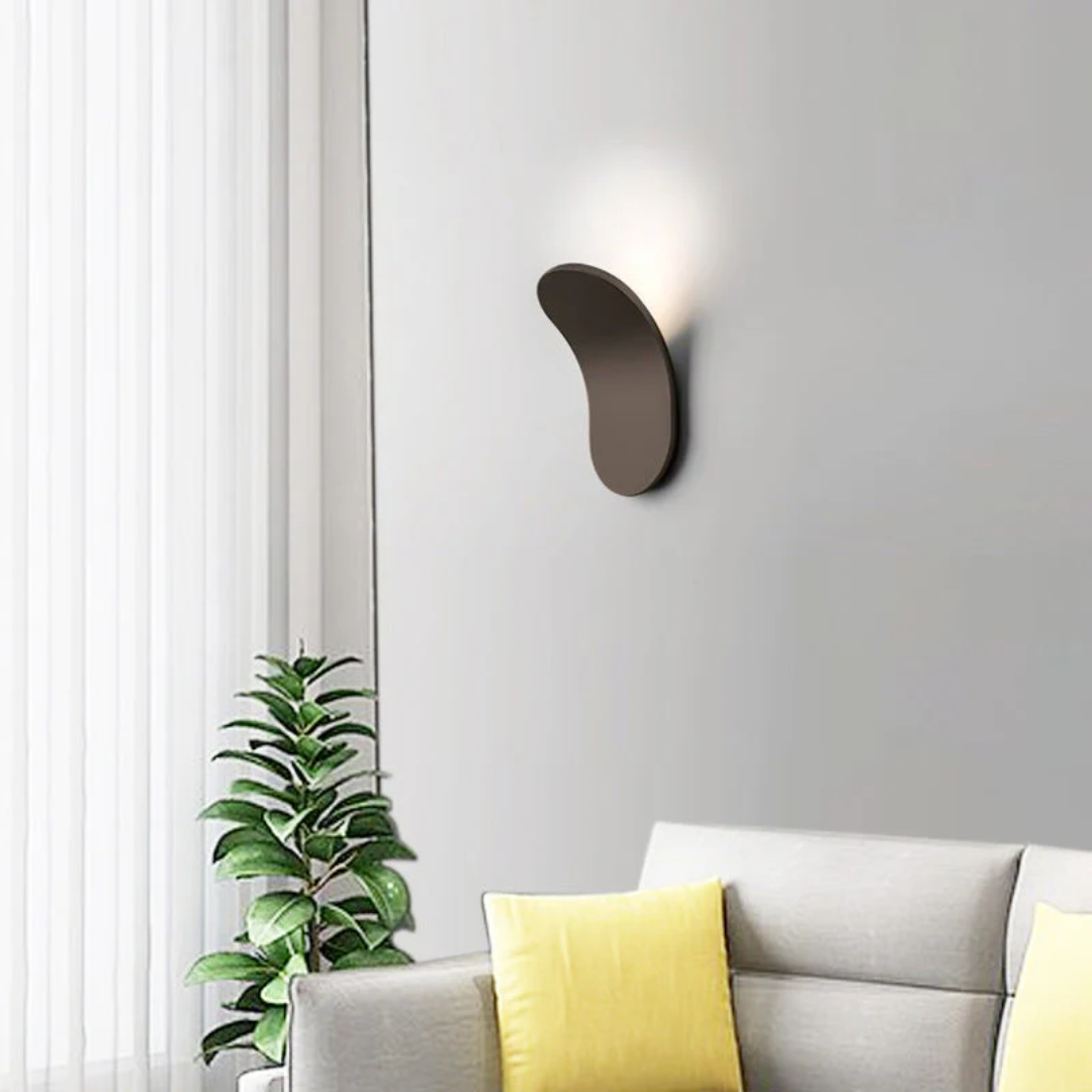Minimalist LED wall sconce with a curved, dark brown design emitting soft light.