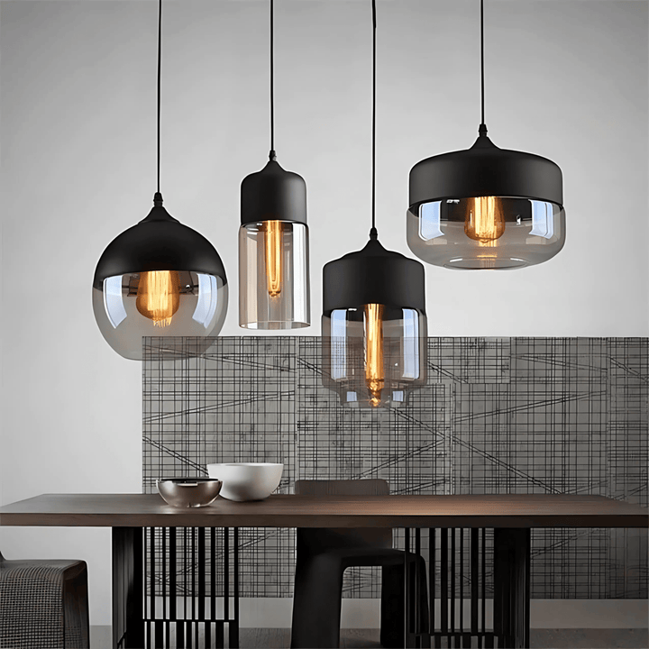 Four Nordic style pendant lights with black metal tops and smoked glass shades, hanging over a wooden table.