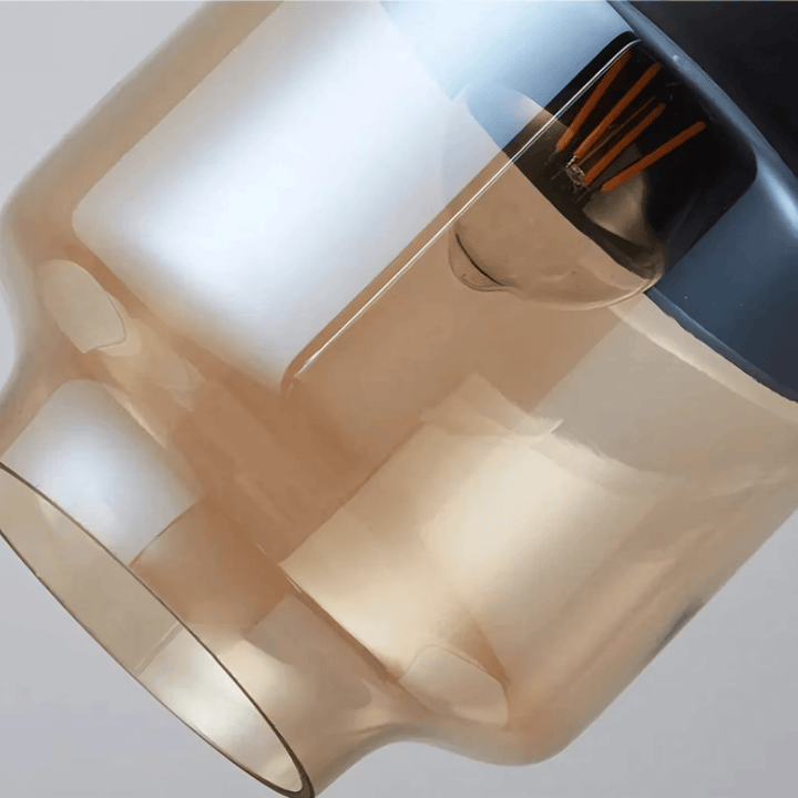 Close-up of a Nordic style pendant light with amber glass and exposed filament bulb.