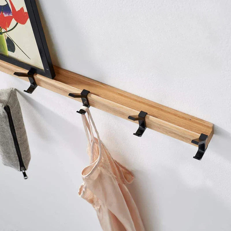 Nordic wall coat rack with natural wood finish and black adjustable hooks, holding a bag and a light pink garment.