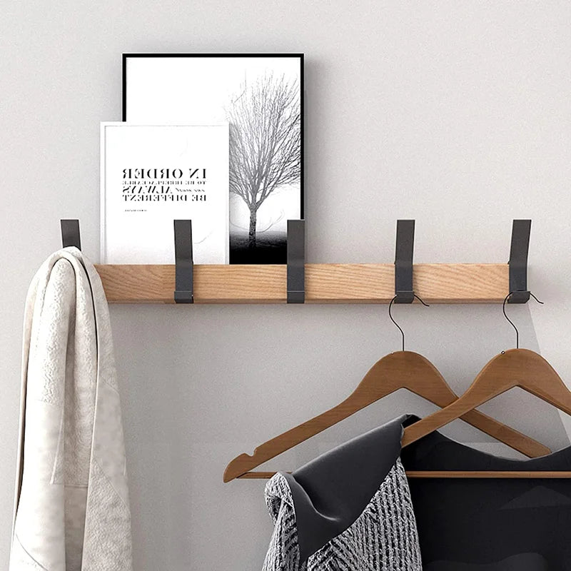 Nordic wall coat rack with natural wood finish and black adjustable hooks, holding a towel and clothes.