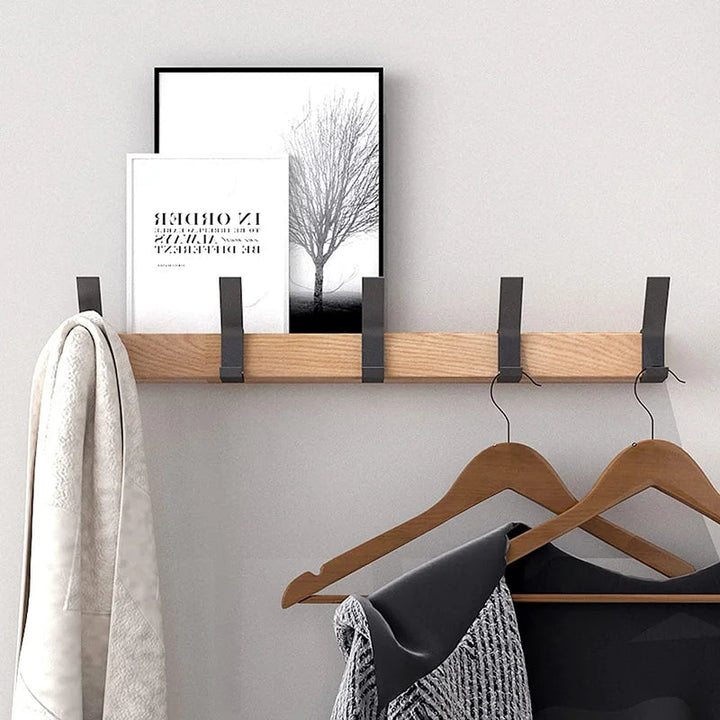 Nordic wall coat rack with natural wood finish and black adjustable hooks, holding a towel and clothes.