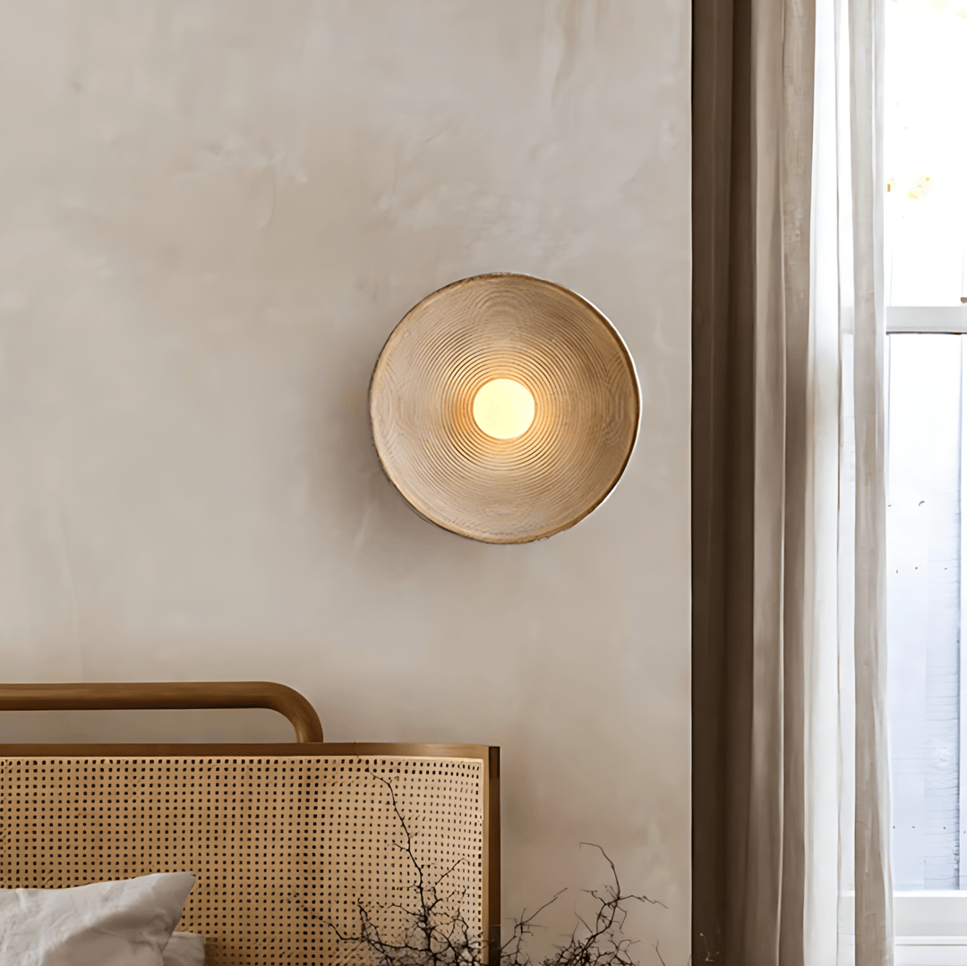 Textured wall sconce with concentric ridges and a warm light.