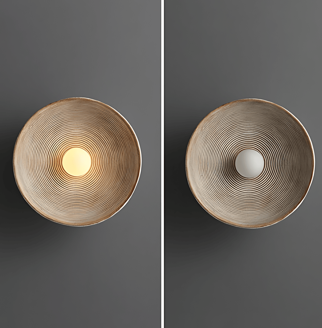 Textured wall sconce with concentric ridges, one lit, one unlit.