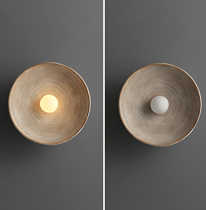 Textured wall sconce with concentric ridges, one lit, one unlit.