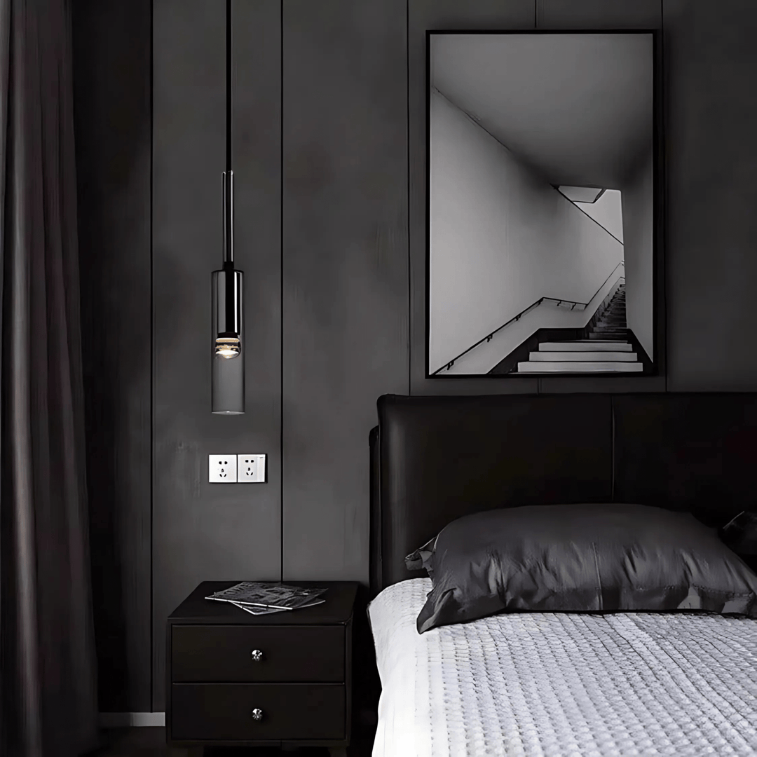Black glass pendant light hanging above a nightstand next to a bed.
