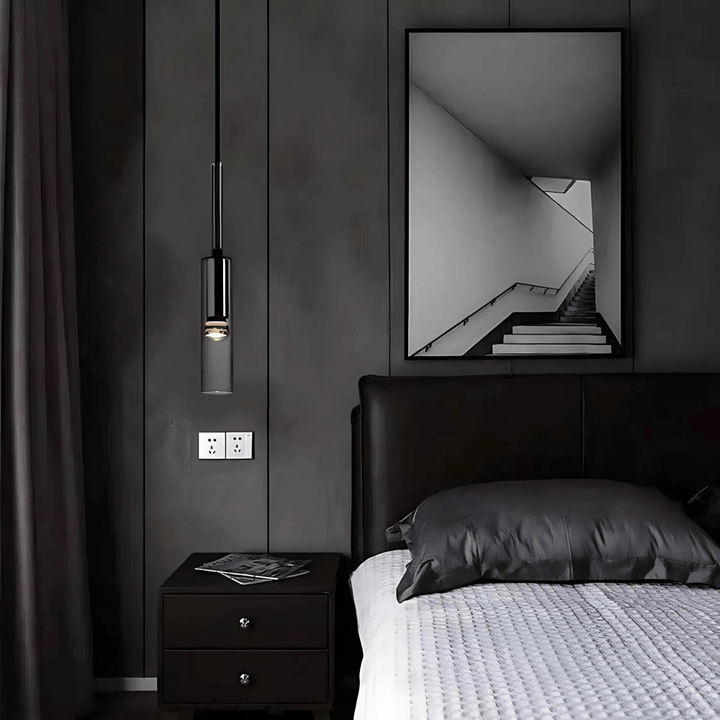Black glass pendant light hanging above a nightstand next to a bed.