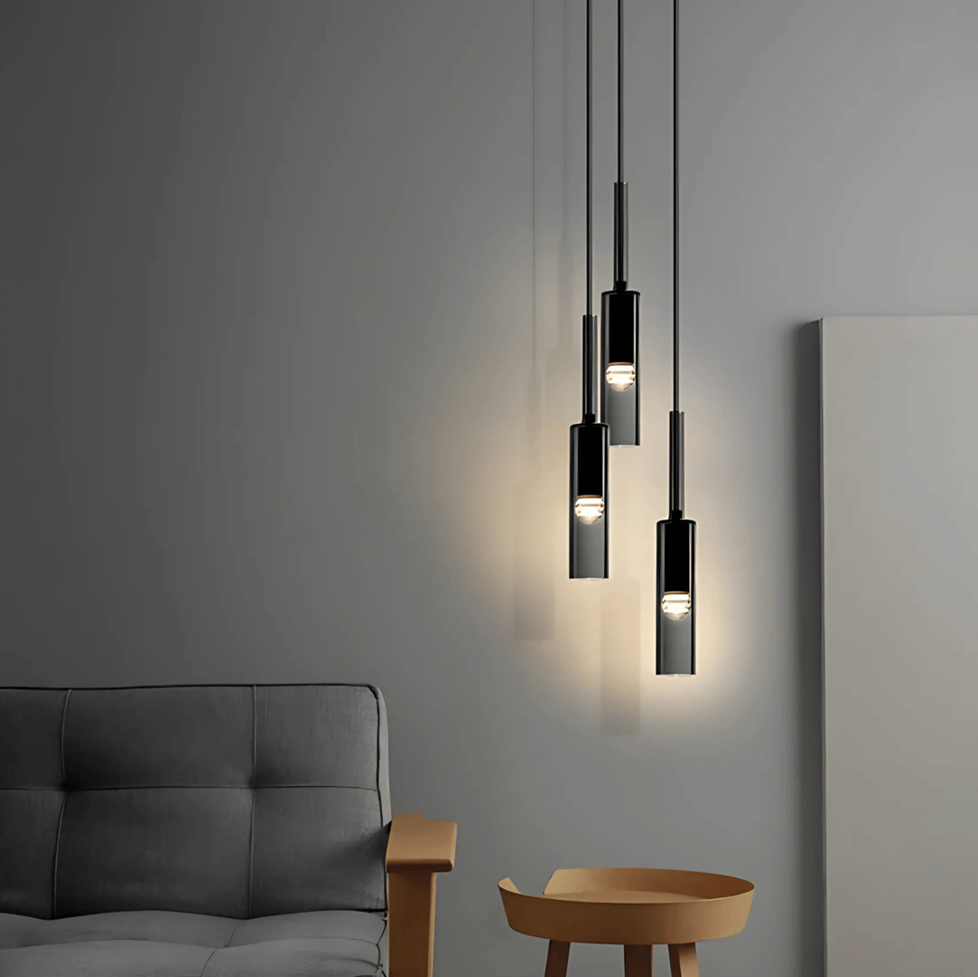 Three black glass pendant lights hanging above a modern sofa and side table.
