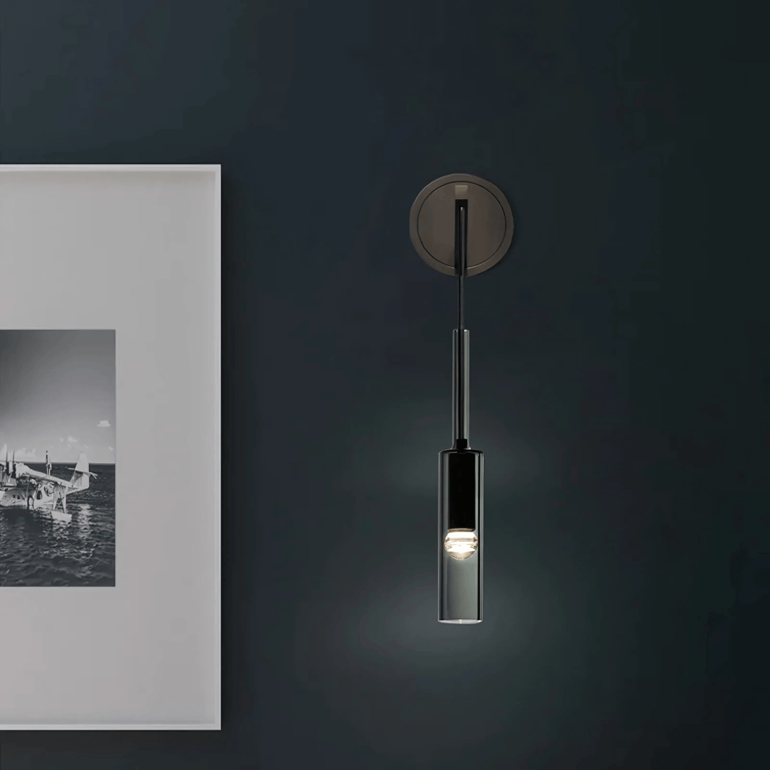 Black glass pendant light with a single bulb hanging from a dark metal fixture against a dark wall.