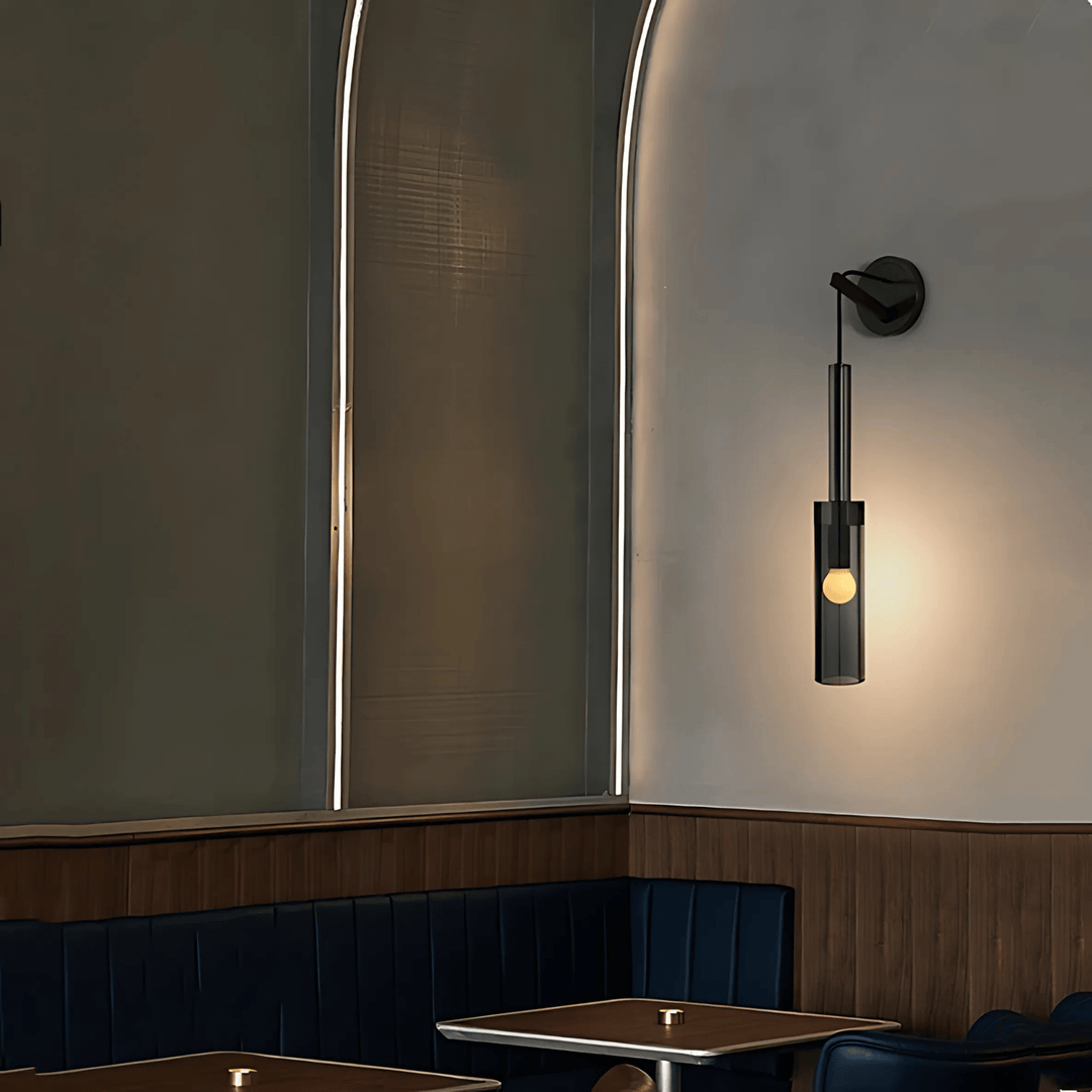 Black glass pendant light with a small bulb inside, hanging above a table in a restaurant booth.