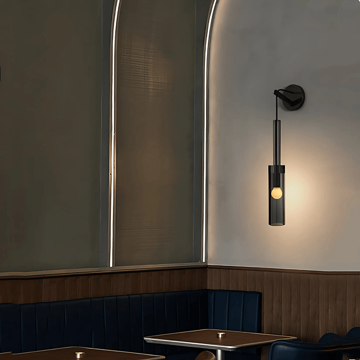 Black glass pendant light with a small bulb inside, hanging above a table in a restaurant booth.