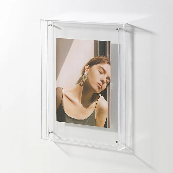 Transparent acrylic picture frame displaying a portrait of a woman with closed eyes and large earrings.