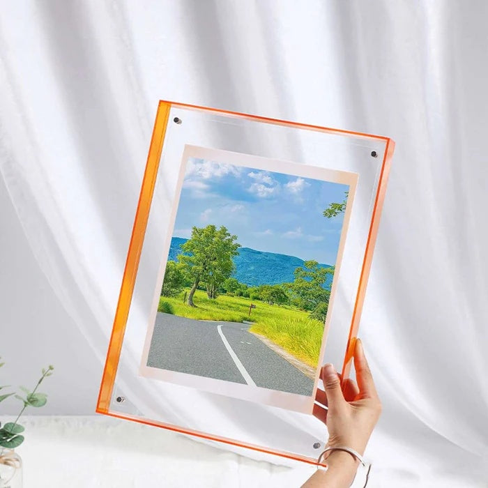 Orange acrylic picture frame holding a landscape photo, displayed against a white curtain.
